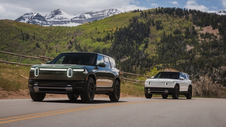 Deux Rivian R2 de série, l'un vert foncé et l'autre blanc, roulant sur une route de montagne en Utah
