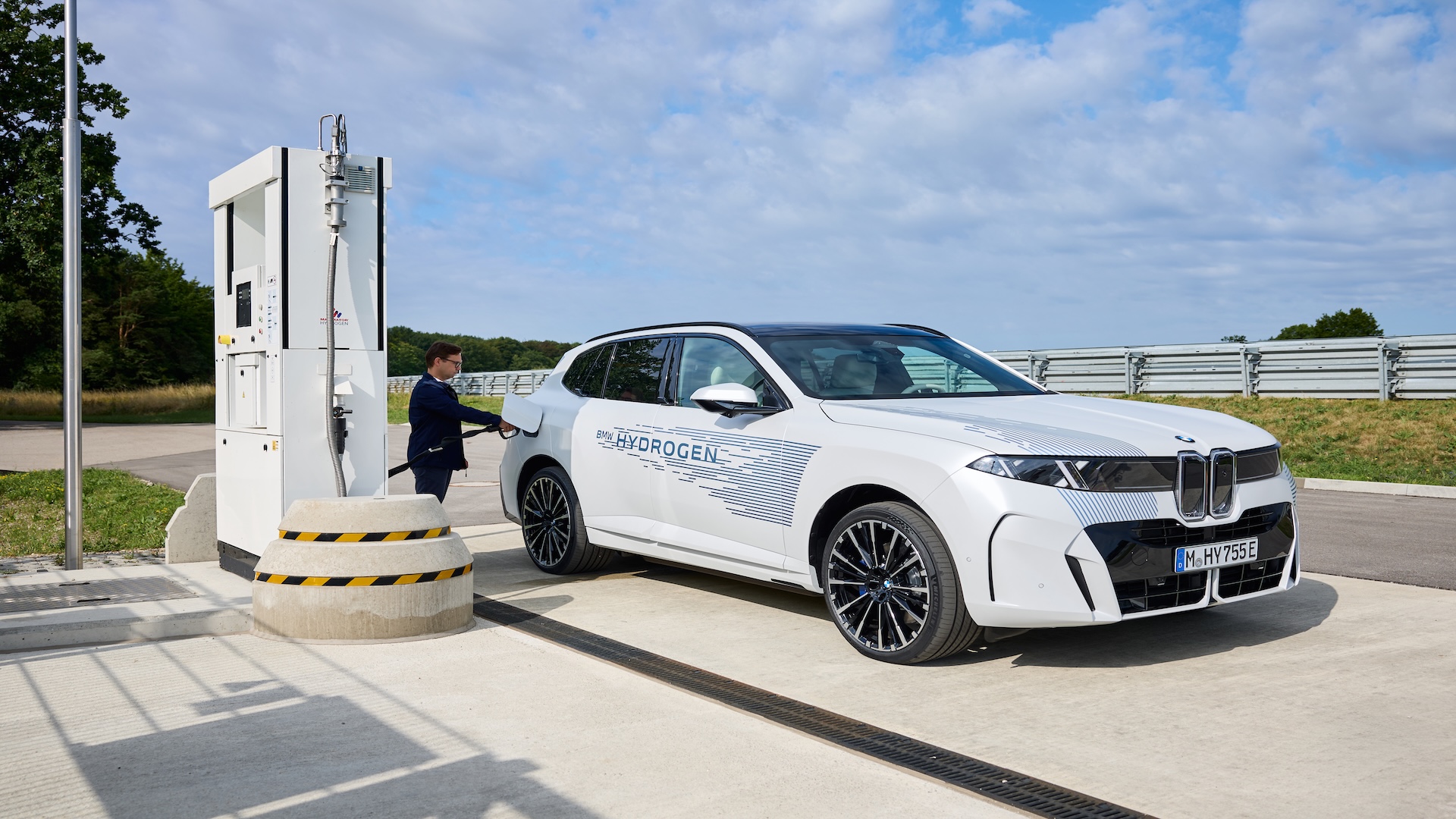 Prototype blanc du BMW iX5 Hydrogen en cours de ravitaillement dans une station d’hydrogène extérieure.