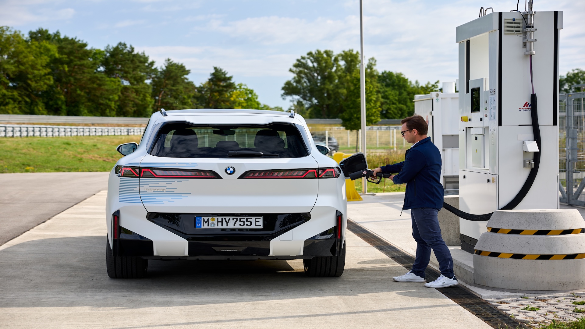 Prototype blanc du BMW iX5 Hydrogen en cours de ravitaillement dans une station d’hydrogène extérieure.