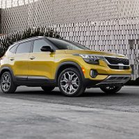 Kia Seltos 2021 de première génération, vue avant trois quarts devant un immeuble | Kia Kia Seltos 2021 jaune vu de l'avant trois quarts