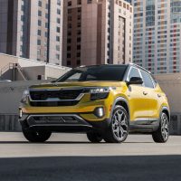 Kia Seltos 2021 stationné en ville, vue avant | Kia Kia Seltos 2021 jaune stationné entre des tours