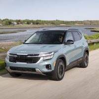 Kia Seltos 2024 restylé, en bleu Pluton, vue avant trois quarts sur la route | Kia Kia Seltos 2024 bleu Pluton qui roule en bord de mer