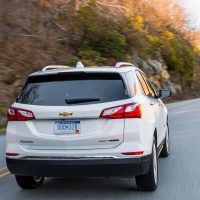 Equinox 2018 blanc Premier AWD, vue trois-quarts arrière en conduite | GM Canada Equinox 2018 blanc Premier AWD, vue trois-quarts arrière en conduite