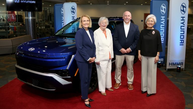 Quatre personnalités sur un tapis rouge à côté d'un VUS Hyundai bleu, à l'usine Hyundai de Montgomery, en Alabama.